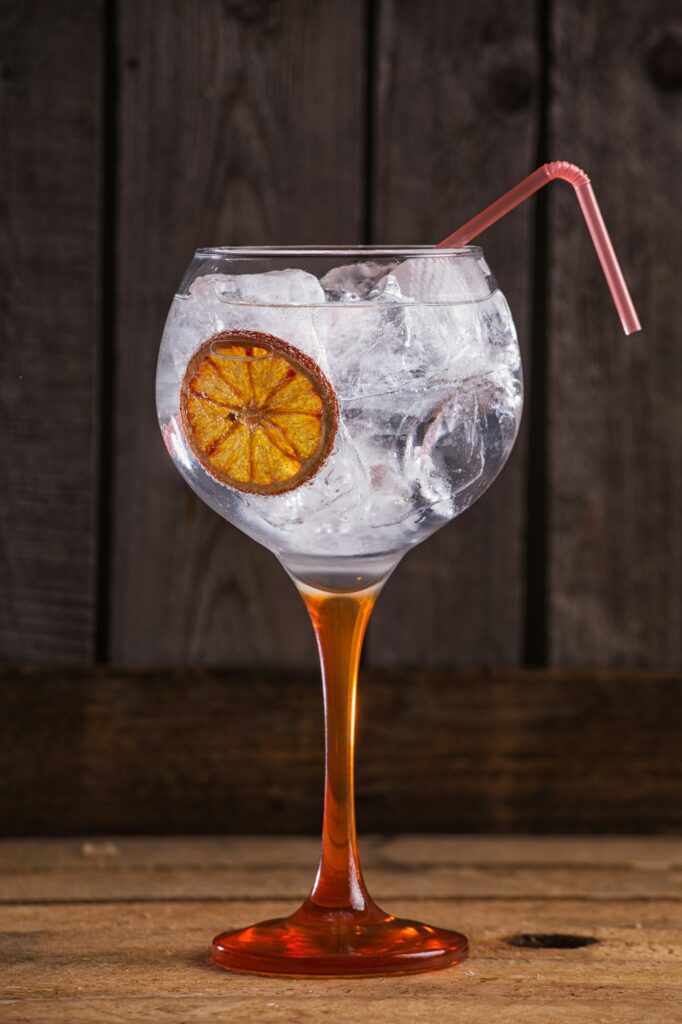 Vertical closeup shot of Gintonic with orange on a wooden table